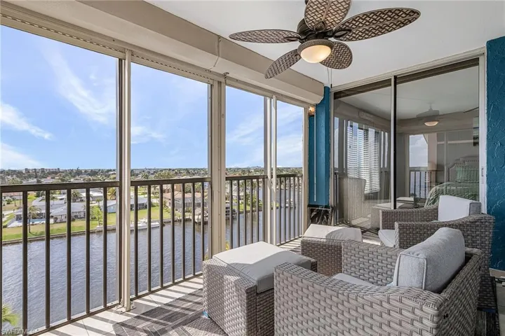 Sunroom with a balcony, a ceiling fan, and a water view