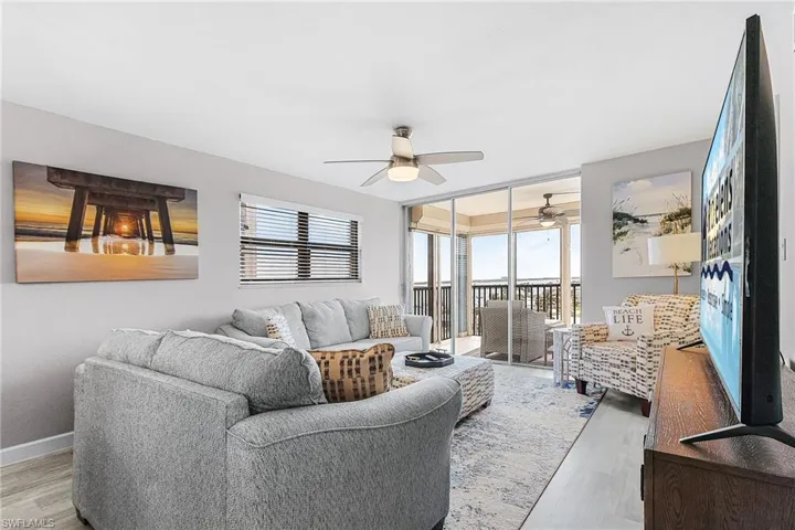Living area with wood finished floors, ceiling fan, and floor to ceiling windows