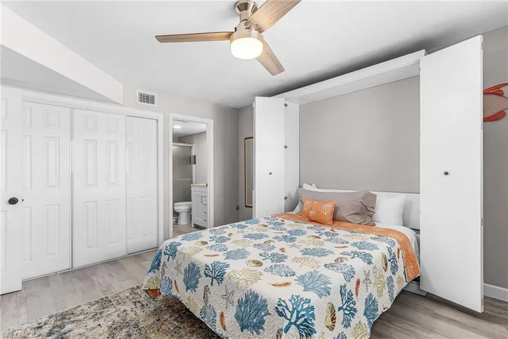Bedroom featuring light wood-style flooring, a ceiling fan, a closet, and ensuite bathroom
