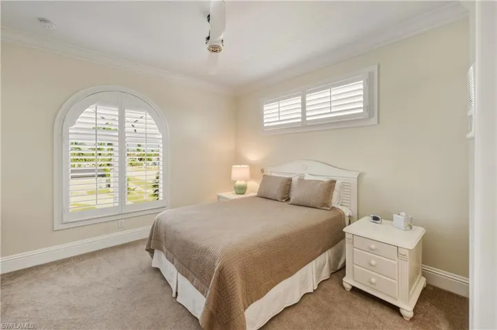 Carpeted bedroom featuring crown molding and baseboards
