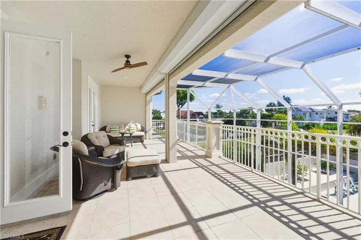 View of patio featuring a sunroom, a ceiling fan, a lanai, and a residential view