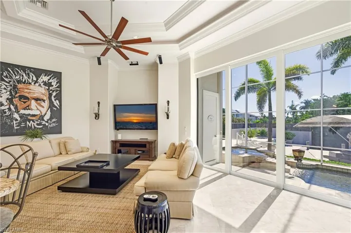 Living area featuring a raised ceiling, crown molding, and a ceiling fan