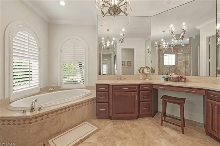 Full bathroom featuring a bath, vanity, crown molding, a stall shower, and a chandelier