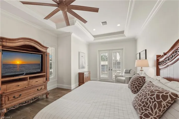 Bedroom with dark wood-style floors, recessed lighting, ornamental molding, a tray ceiling, and ceiling fan