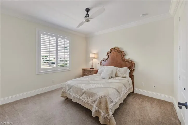 Carpeted bedroom featuring crown molding and a ceiling fan