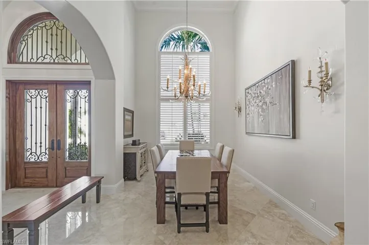 Dining area featuring a towering ceiling, a chandelier, french doors, and crown molding