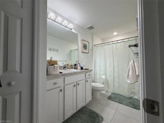 Full bathroom featuring a single vanity with white cabinetry, a large wall mirror, and modern overhead lighting