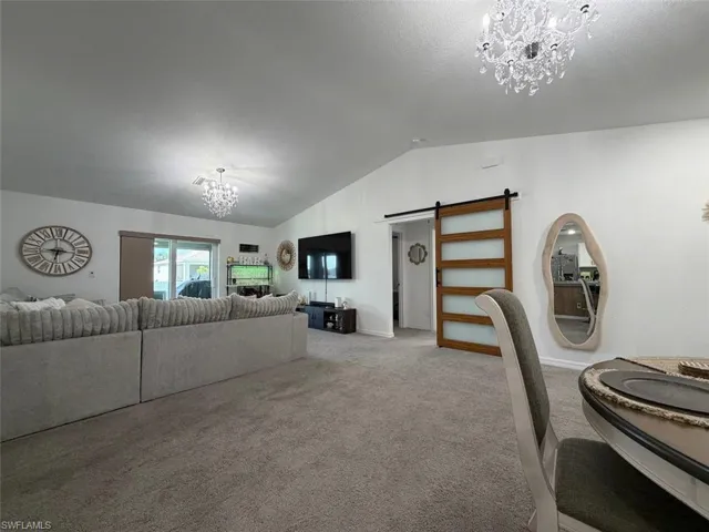 Spacious interior featuring a vaulted ceiling, sliding glass doors, and a wood-finish barn door with frosted glass panels