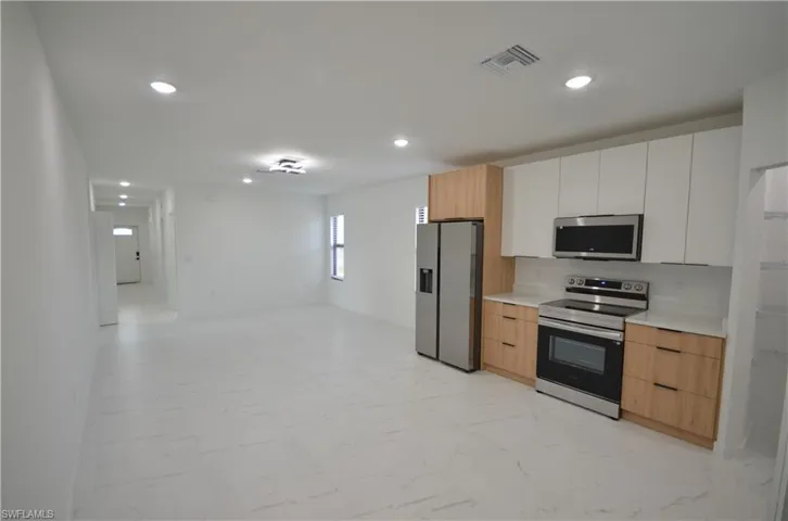 Kitchen with modern cabinets, stainless steel fridge, marble finish floor, and recessed lighting