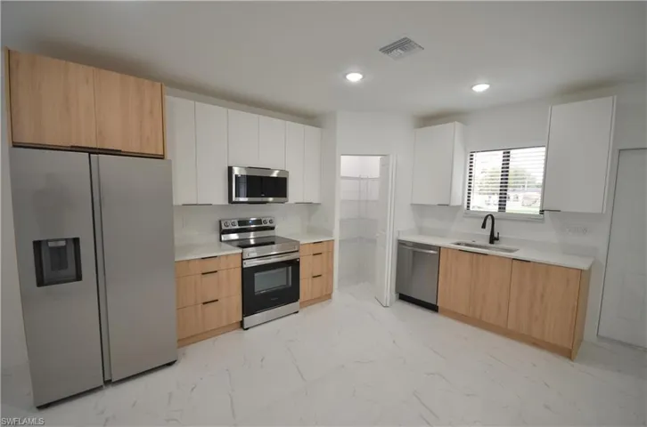 Kitchen featuring light countertops, modern cabinets, marble finish floor, and appliances with stainless steel finishes