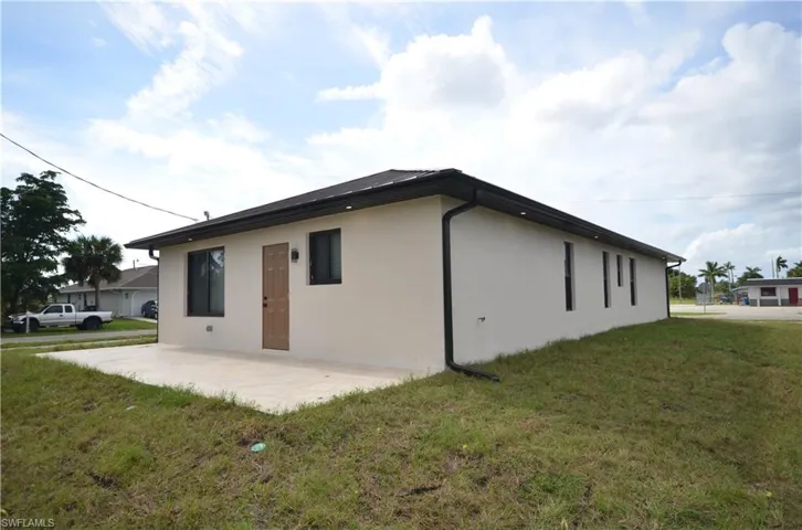 Back of property featuring stucco siding, a lawn, and a patio area