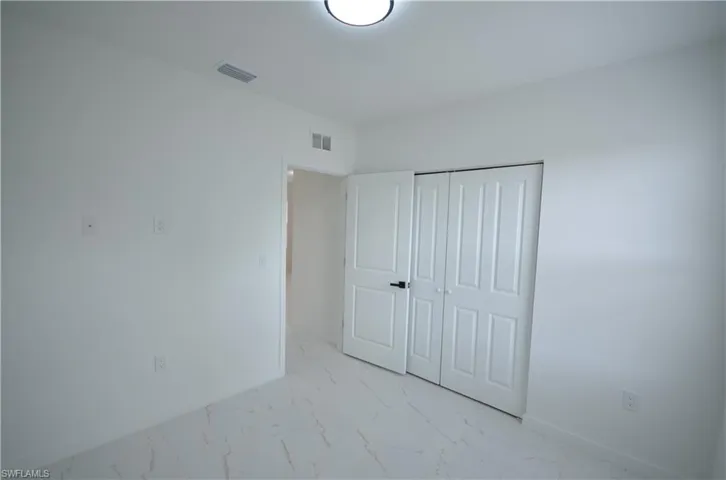 Unfurnished bedroom with visible vents, marble finish floor, a closet, ceiling fan, and a spacious closet