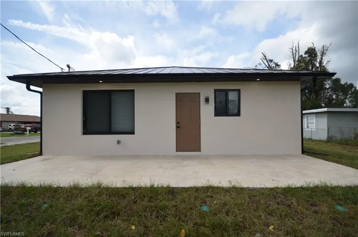 View of front of home with a patio area, stucco siding, metal roof, and a standing seam roof