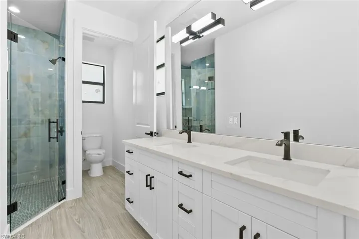 Full bath featuring double vanity and a shower stall