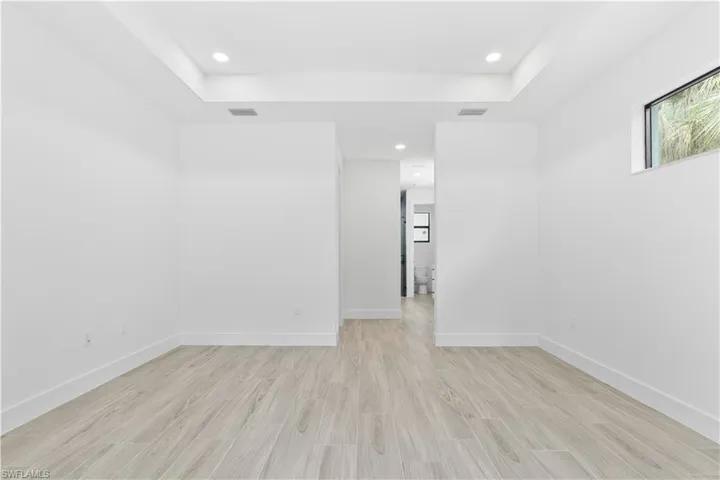 Unfurnished room with light wood-style flooring, recessed lighting, and a tray ceiling