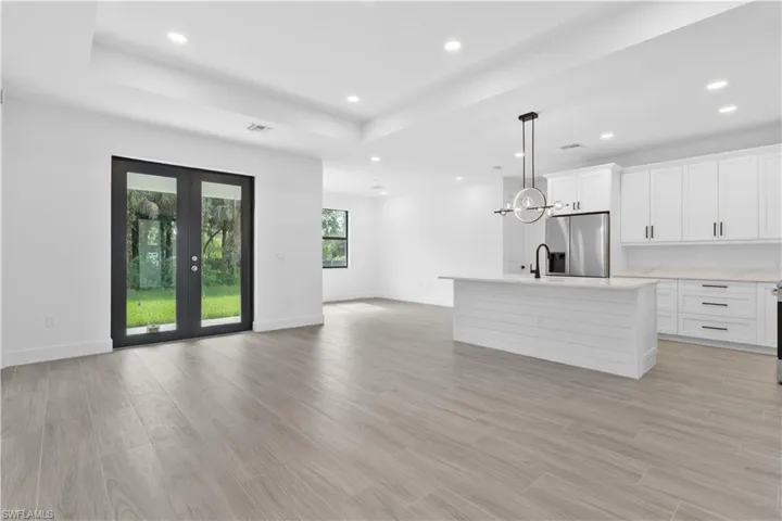 Kitchen with white cabinets, light wood finished floors, open floor plan, decorative light fixtures, and recessed lighting