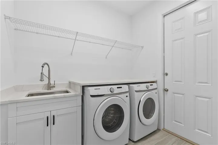 Laundry area with washing machine and dryer, light wood-style floors, and cabinet space
