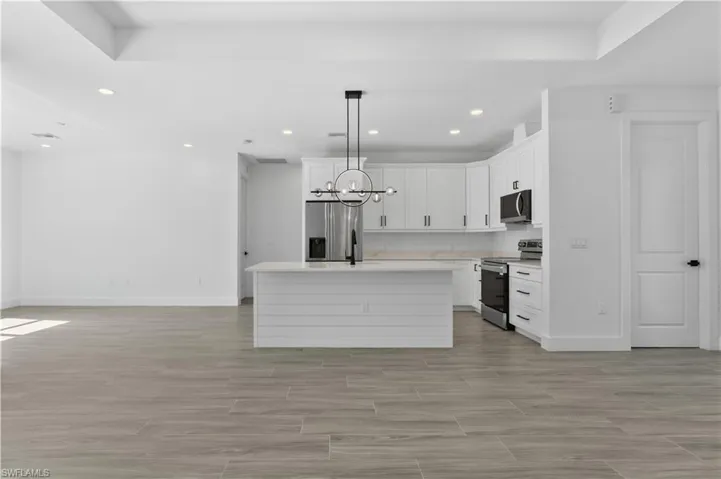 Kitchen with open floor plan, recessed lighting, stainless steel appliances, pendant lighting, and white cabinetry