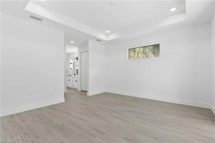 Empty room with a raised ceiling, wood finish floors, and recessed lighting