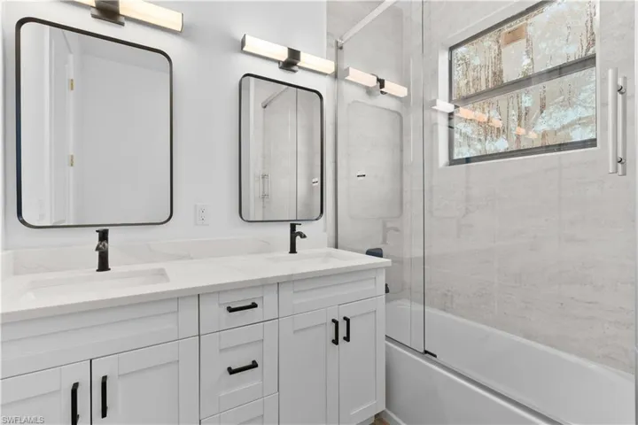 Full bath featuring shower / bath combination with glass door and double vanity
