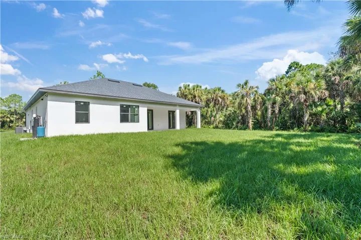 Rear view of property with stucco siding, a patio area, and a lawn