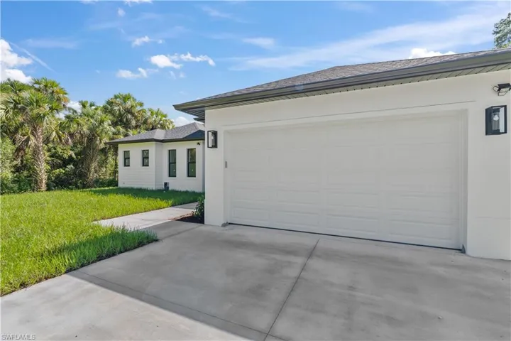 View of front facade with concrete driveway, a front yard, a garage, and stucco siding