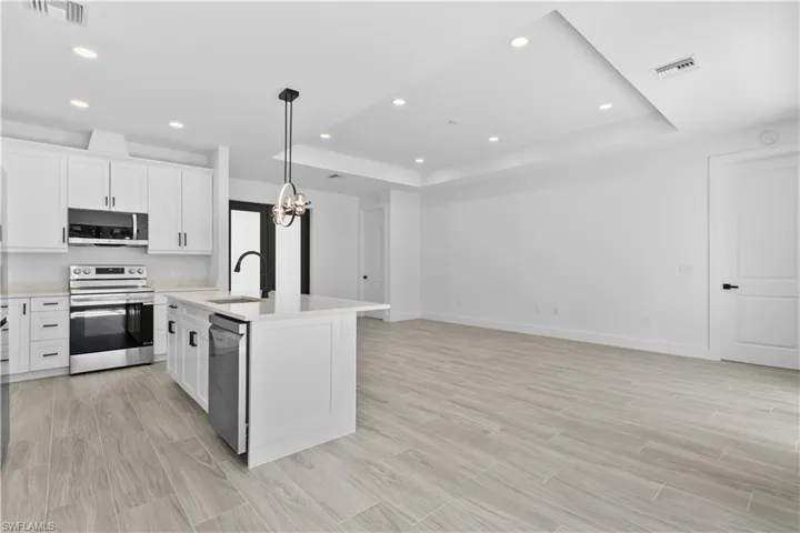 Kitchen featuring white cabinetry, wood finish floors, appliances with stainless steel finishes, pendant lighting, and recessed lighting