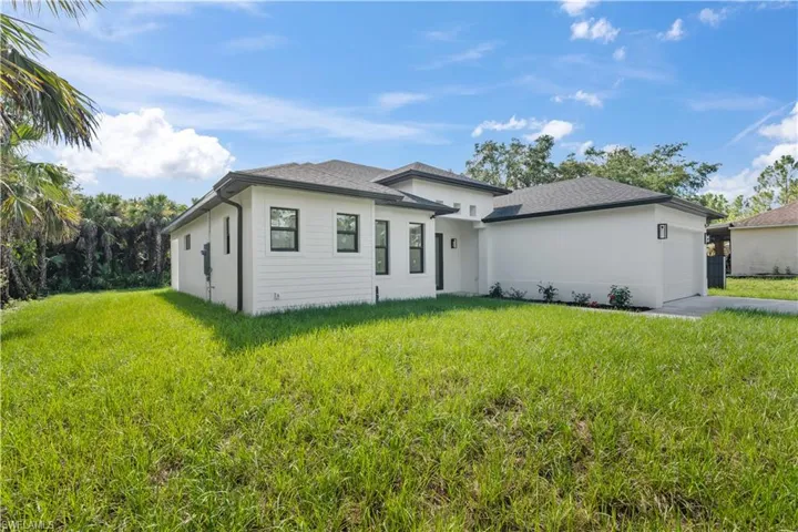 Prairie-style house featuring an attached garage, stucco siding, concrete driveway, and a front lawn