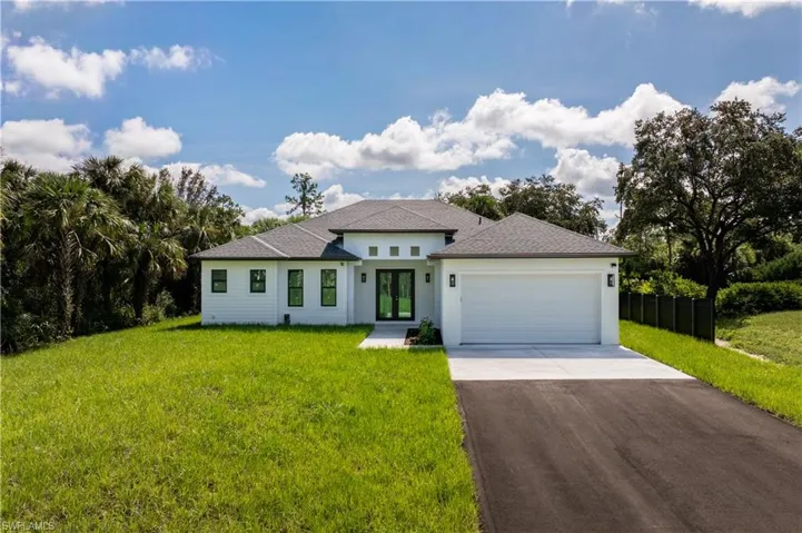 Prairie-style home featuring driveway, an attached garage, a shingled roof, and stucco siding