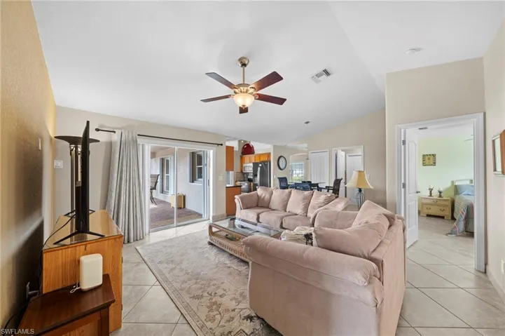 Living area with light tile patterned floors, vaulted ceiling, and ceiling fan