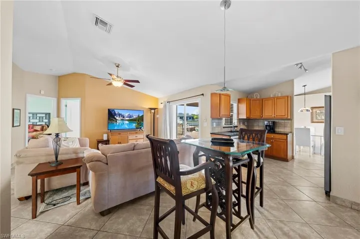 Dining area with lofted ceiling, light tile patterned floors, and ceiling fan