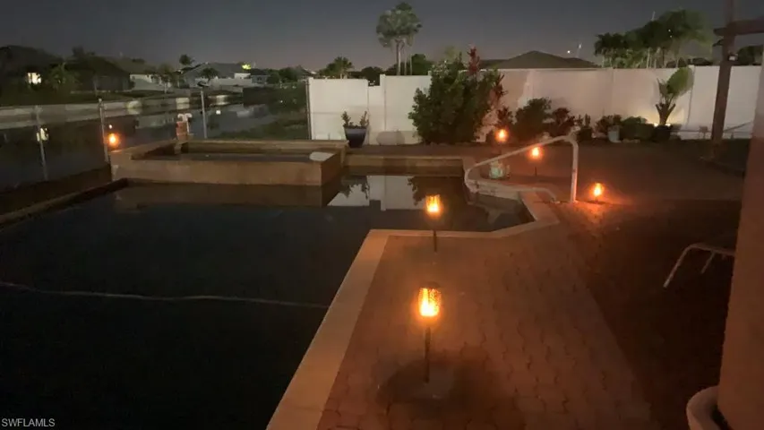 Pool at twilight with a patio and a fenced backyard