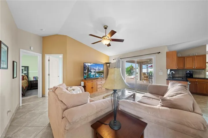 Living area featuring vaulted ceiling, a ceiling fan, and light tile patterned flooring