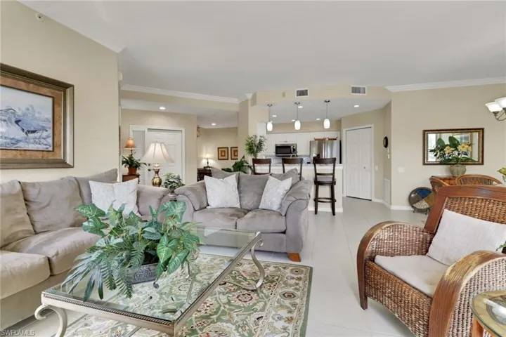 Living room featuring light tile patterned floors, ornamental molding, and recessed lighting