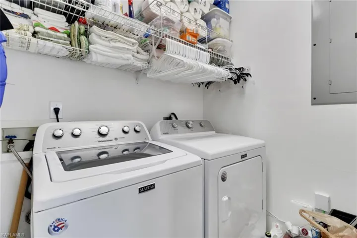 Washroom featuring electric panel and washer and clothes dryer