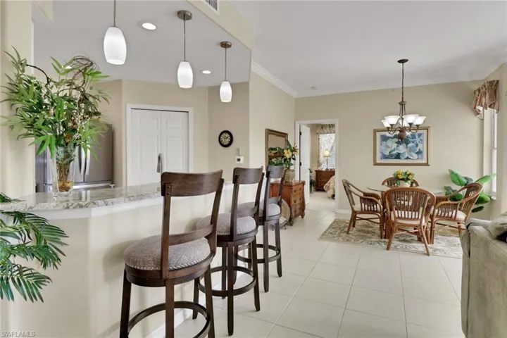 Kitchen featuring hanging light fixtures, light stone countertops, a kitchen bar, light tile patterned flooring, and a peninsula
