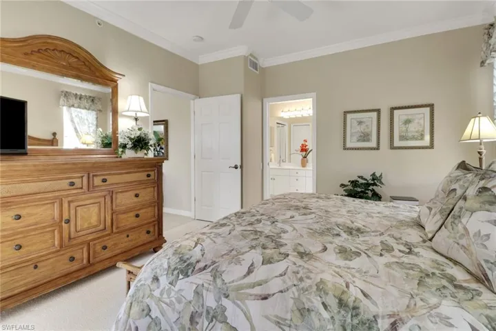Bedroom featuring ornamental molding, light colored carpet, ceiling fan, and ensuite bath