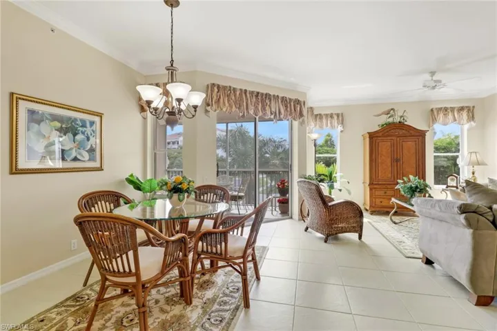 Dining area featuring crown molding, light tile patterned floors, a chandelier, and ceiling fan