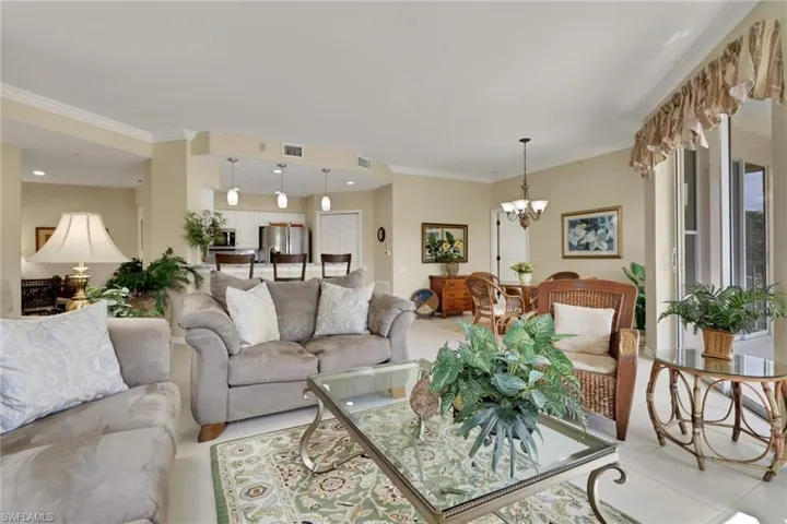 Living room with tile patterned floors, ornamental molding, and a chandelier