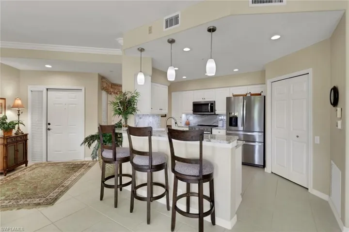 Kitchen with a peninsula, a breakfast bar area, white cabinets, stainless steel appliances, and tasteful backsplash