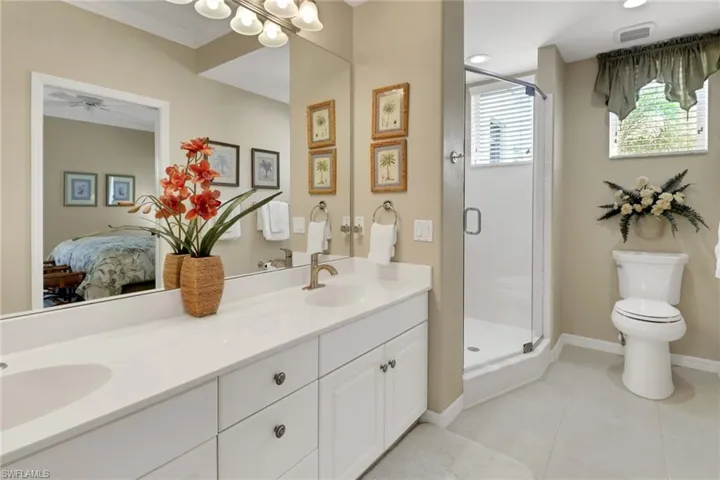 Bathroom featuring double vanity, a shower stall, light tile patterned floors, and connected bathroom