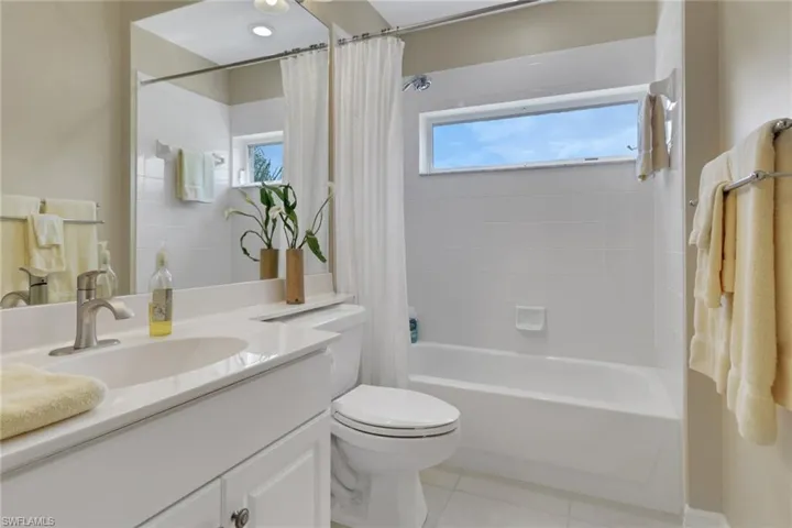 Full bathroom featuring shower / bath combo, vanity, light tile patterned floors, and plenty of natural light