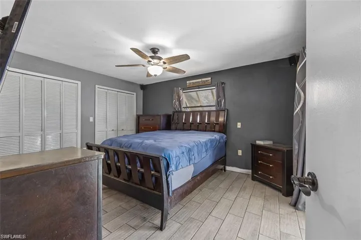 Bedroom with ceiling fan, light wood-type flooring, and two closets