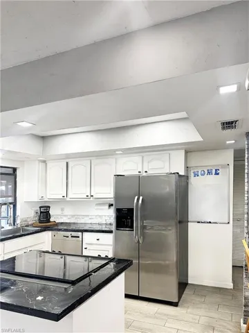 Kitchen featuring a sink, white cabinetry, stainless steel fridge, dishwashing machine, and wood tiled floor