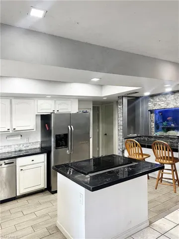 Kitchen with dark countertops, white cabinets, appliances with stainless steel finishes, and wood finish floors