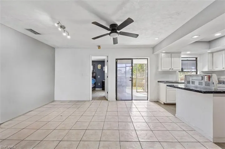 Kitchen featuring white cabinets, ceiling fan, dark stone countertops, and light tile patterned floors