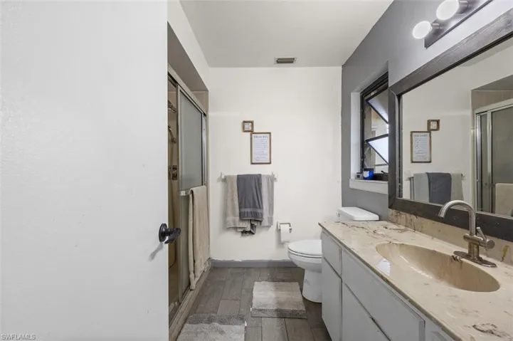 Bathroom with walk in shower, wood-type flooring, vanity, and toilet