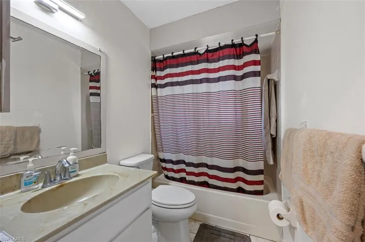 Full bathroom with vanity, shower / tub combo with curtain, tile patterned flooring, and toilet