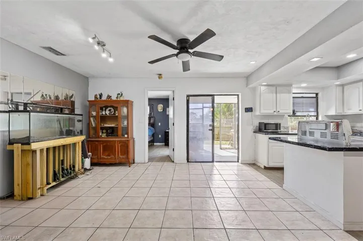 Kitchen with white cabinetry, light tile patterned floors, ceiling fan, and dark stone countertops