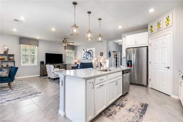 Kitchen with open floor plan, white cabinets, decorative light fixtures, appliances with stainless steel finishes, and a ceiling fan